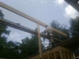 Carpenter setting a ridge beam over a new addition frame — Ice Dam Removal by Roofing Brothers in Leonidas