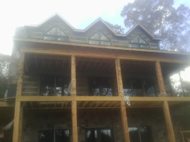 Dormers and porch framing on a large log home under construction — Roof Coating work by our crew in Leonidas