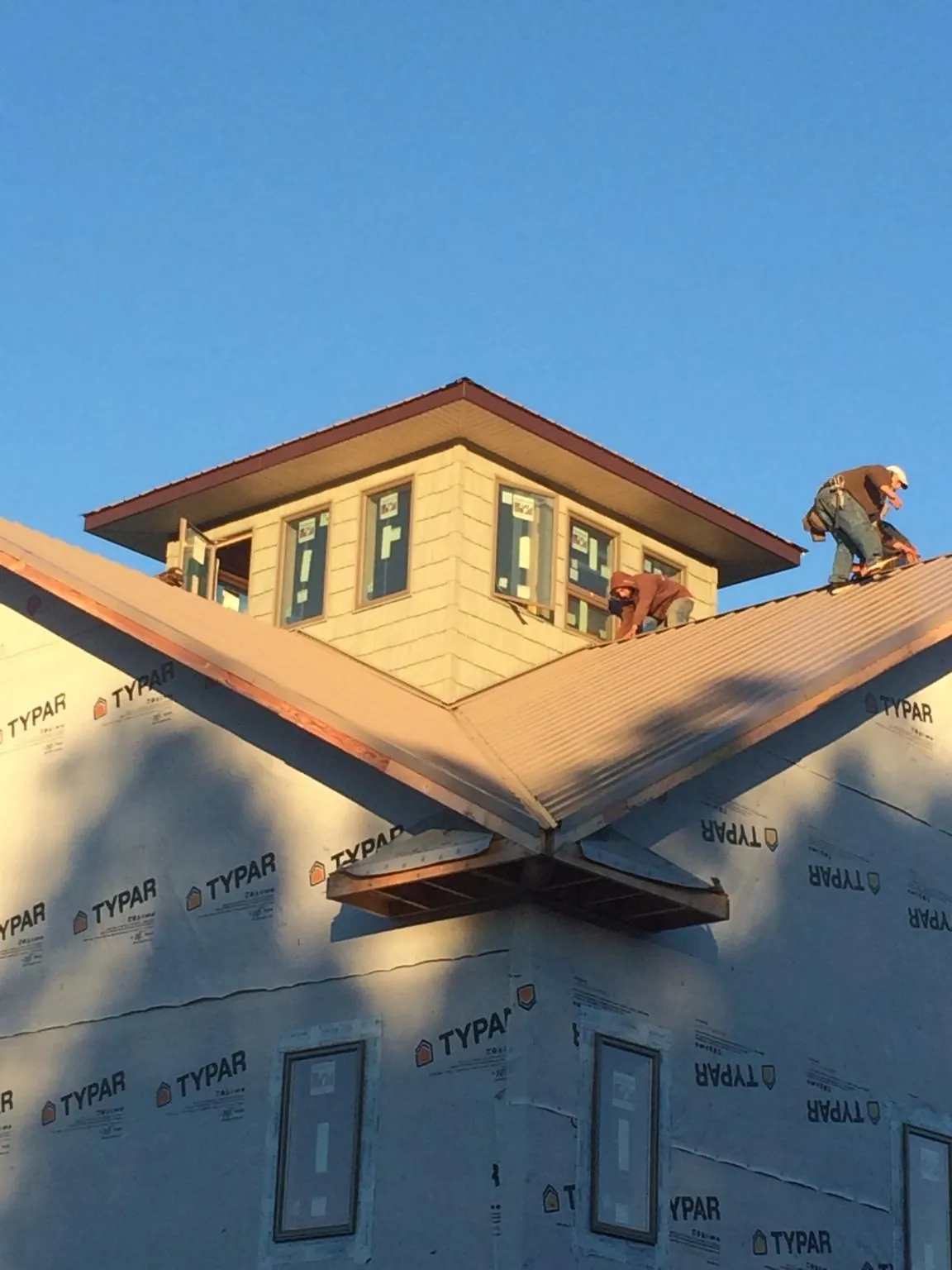 Roofers working around a rooftop cupola on a new metal roof at sunset — Roof Waterproofing in Leonidas by Roofing Brothers